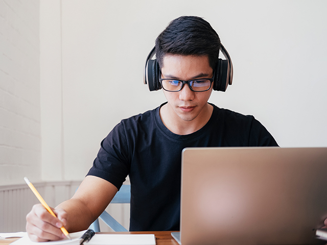 student-works-on-laptop-with-headphones